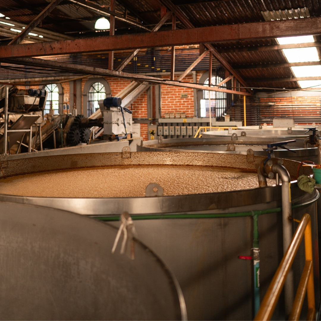 Fermentation tanks in a tequila distillery with a sign reading 'FERMENTACION'.